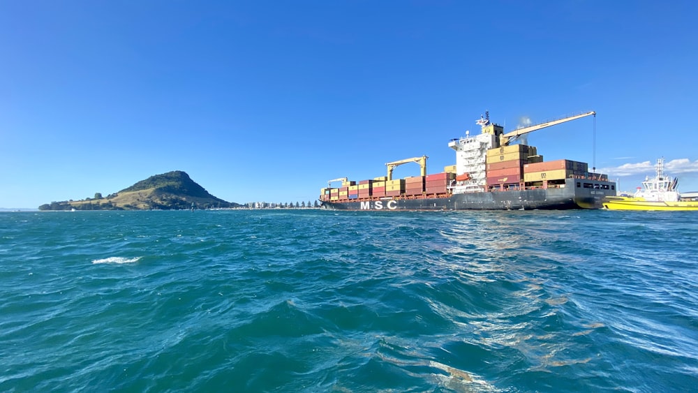 red cargo ship on sea under blue sky during daytime