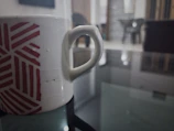 Close-up of a white mug with a colorful geek-themed design on a wooden table.