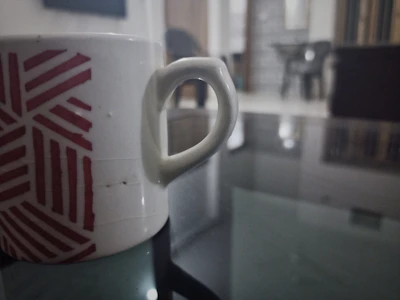 Close-up of a white mug with a colorful geek-themed design on a wooden table.
