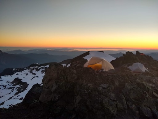 A cozy mountain camp setup at sunset with tents and a campfire near the Patagonian wilderness.