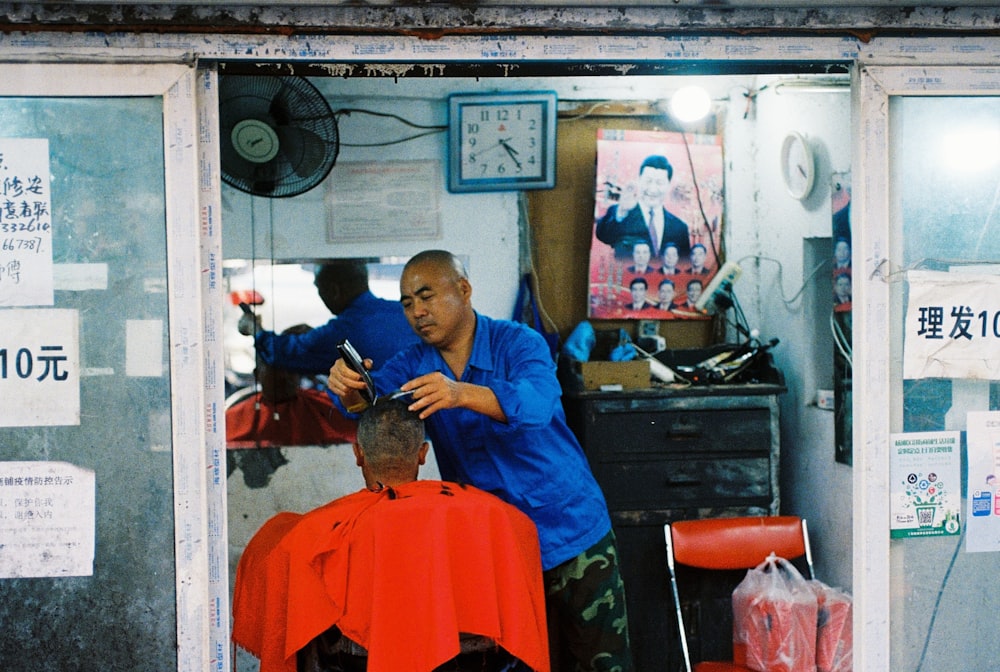 man in blue scrub suit sitting on barber chair