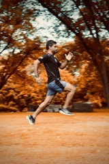 man in black t-shirt and black shorts running on brown field