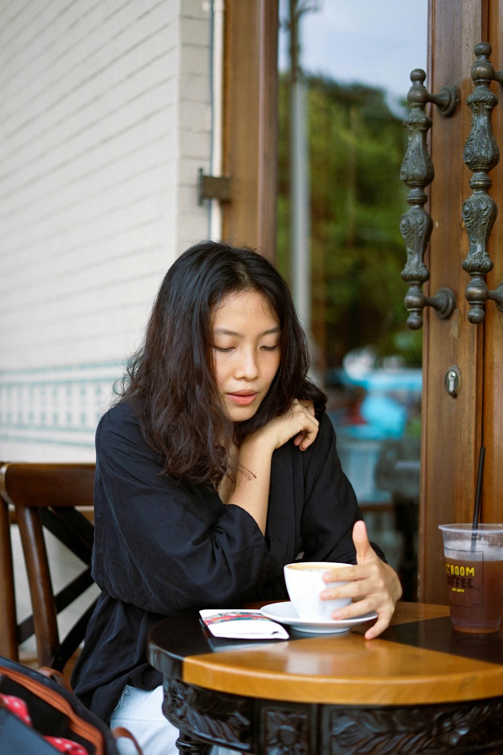 woman in black long sleeve shirt sitting on brown wooden chair