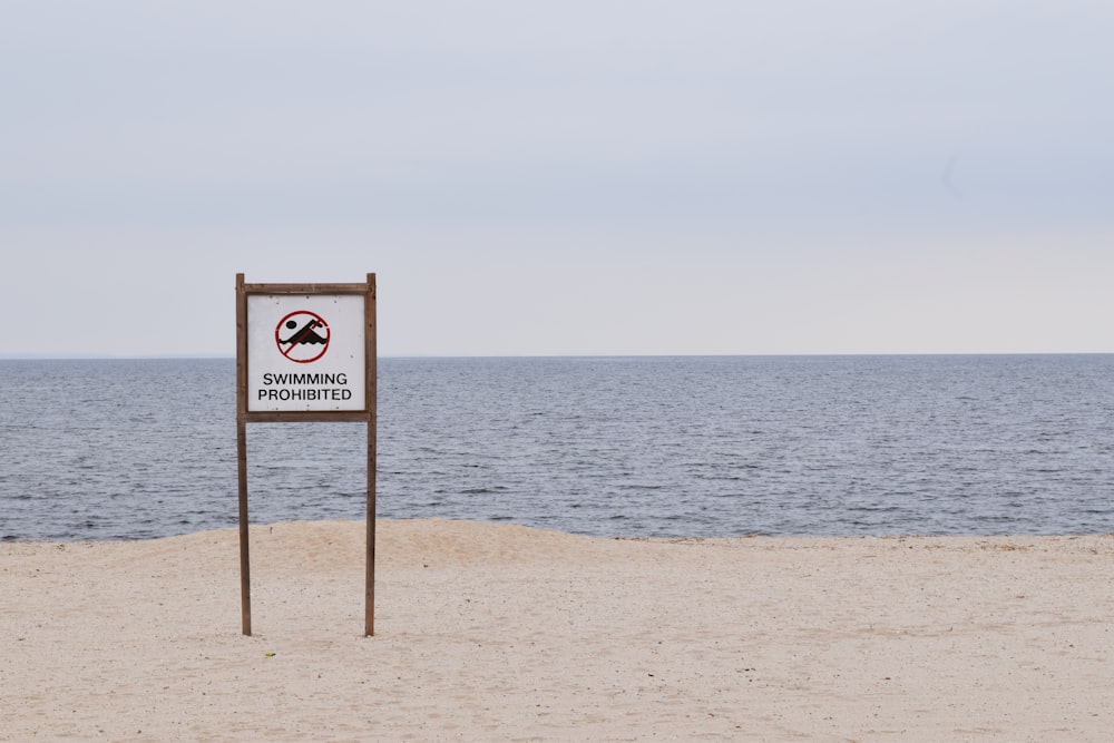 sinalização de praia marrom e branca na praia durante o dia