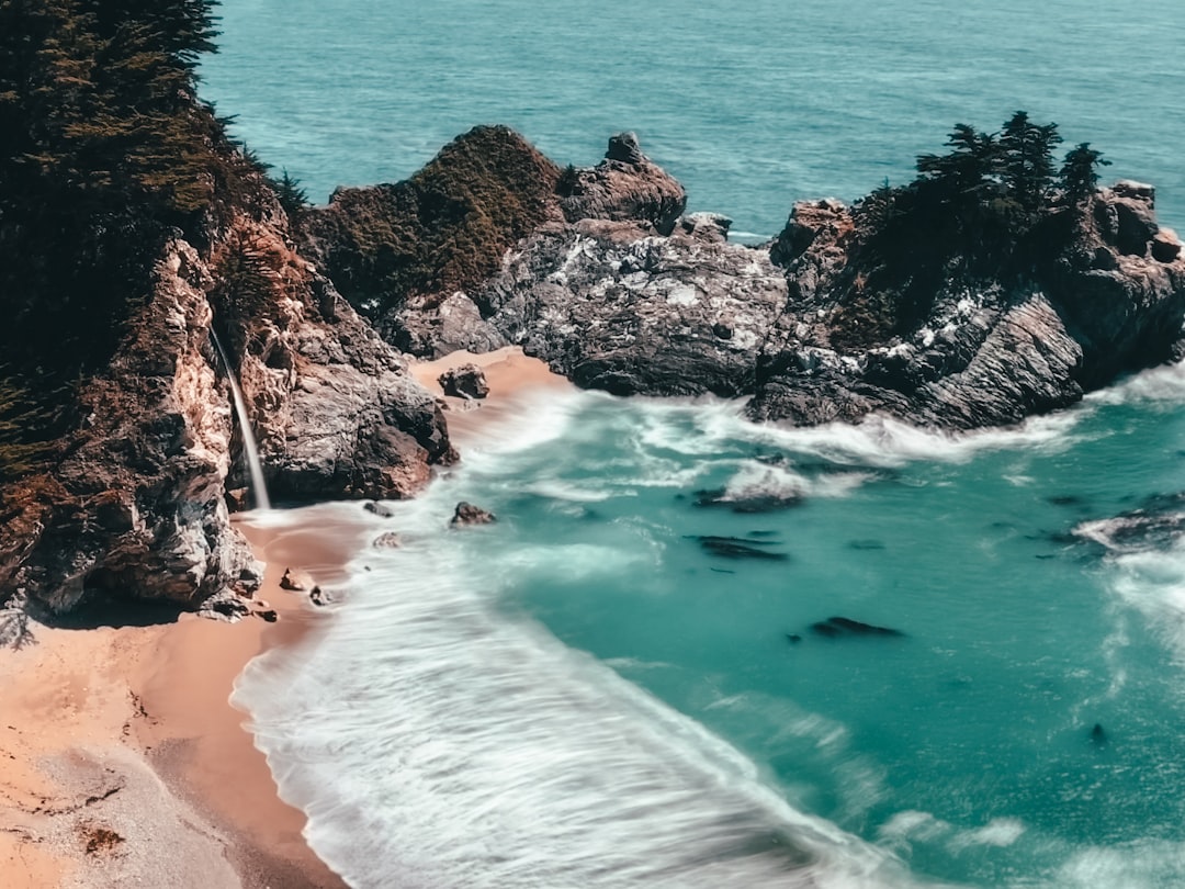 brown rocky mountain beside sea during daytime