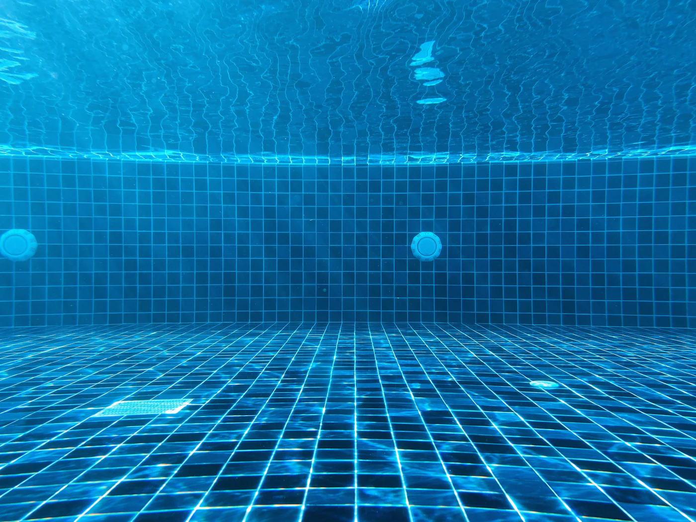 Underwater view of a blue tiled swimming pool with circulating water