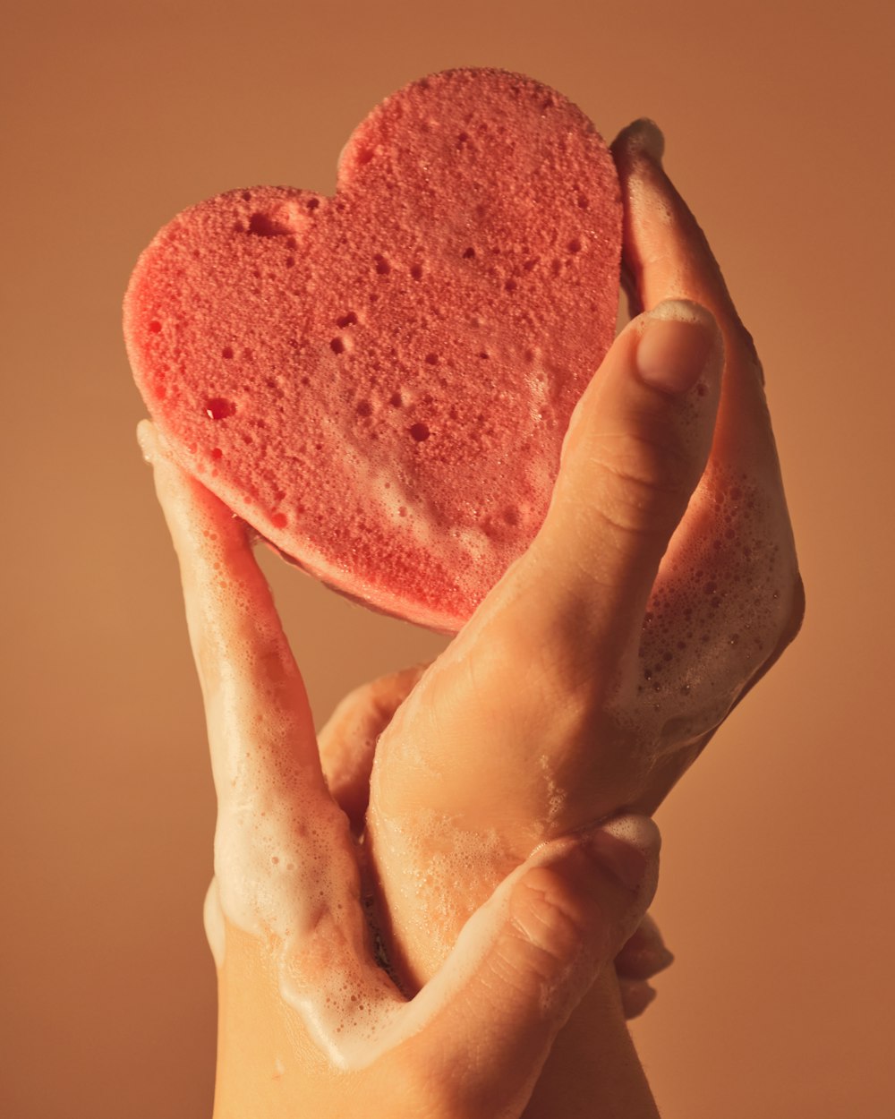 Persona che tiene la torta rosa a forma di cuore