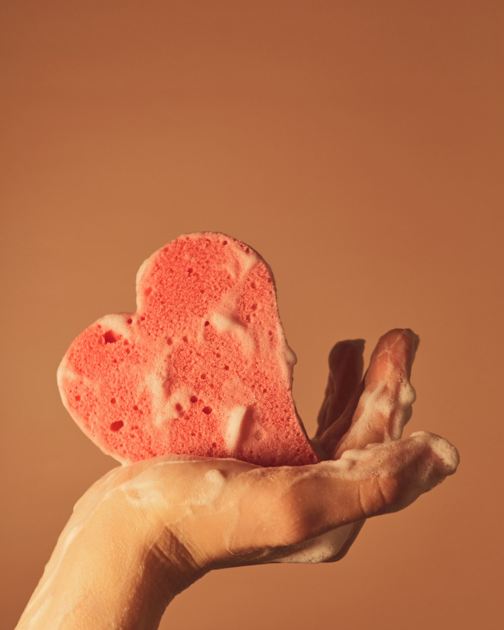 Persona sosteniendo adorno rosa en forma de corazón