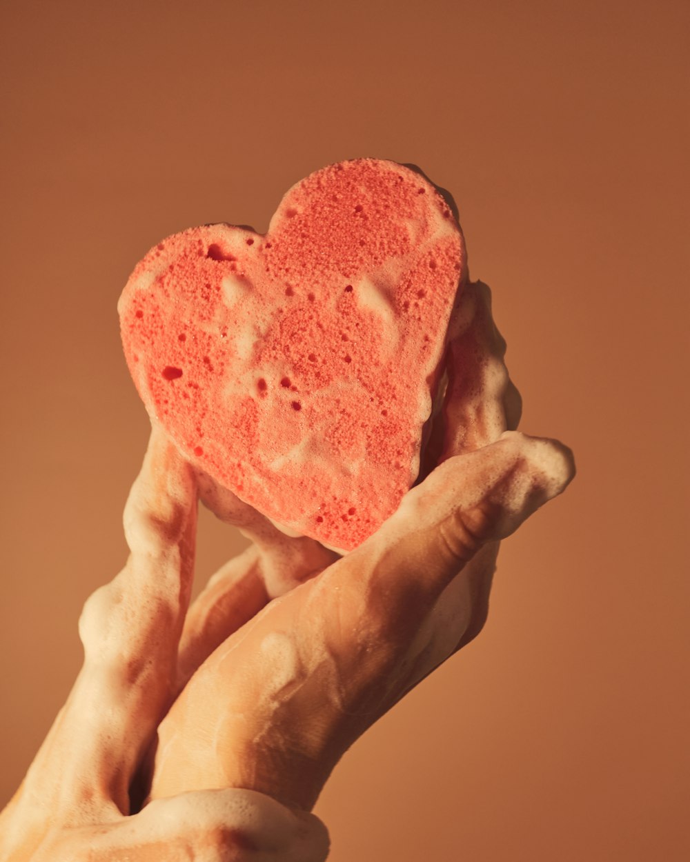 Persona sosteniendo un helado rojo en forma de corazón