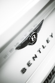 Close-up of a Bentley's signature grille and emblem with red accent lighting highlighting the contours.