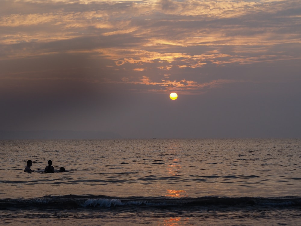 silhouette of 2 people on sea during sunset