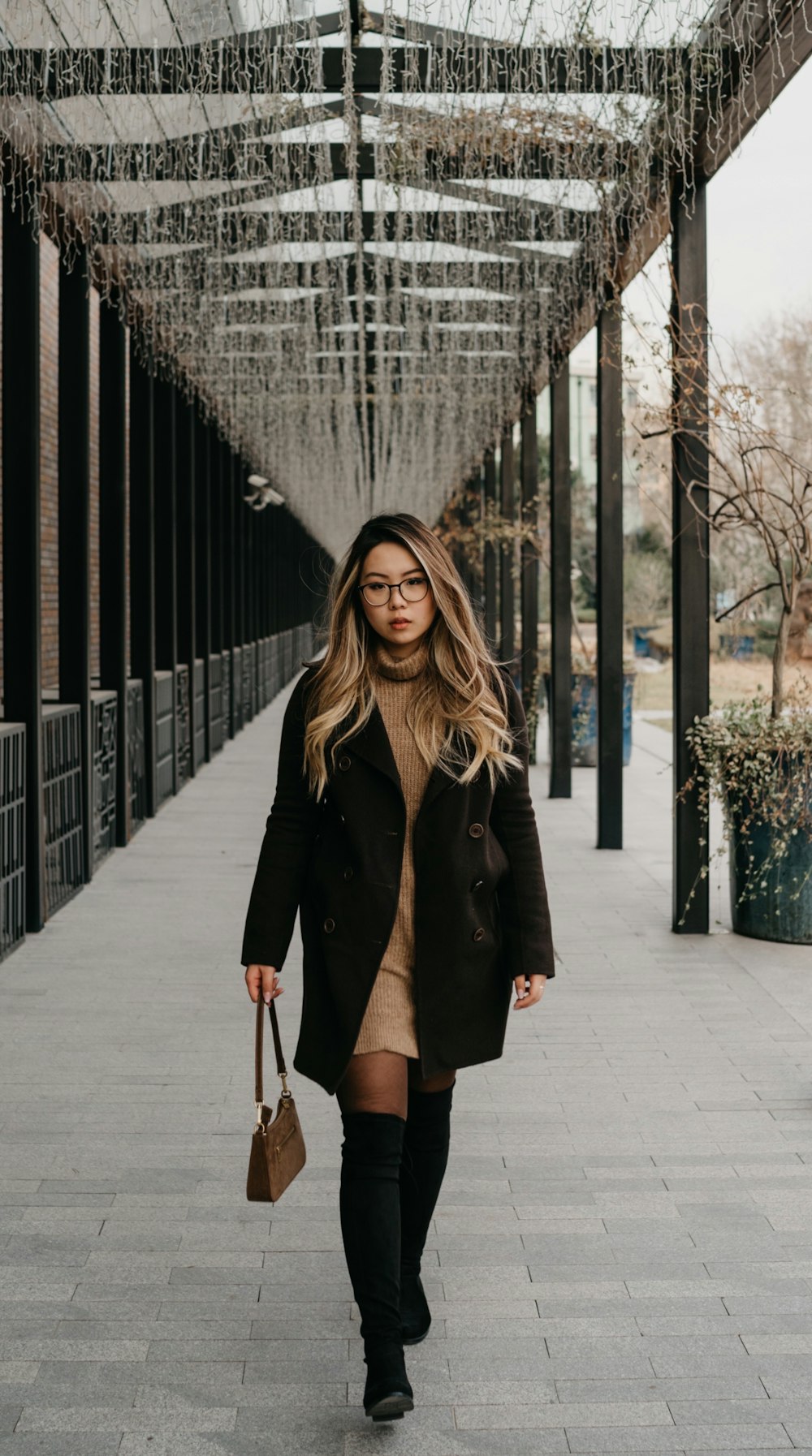 woman in black coat standing on sidewalk during daytime