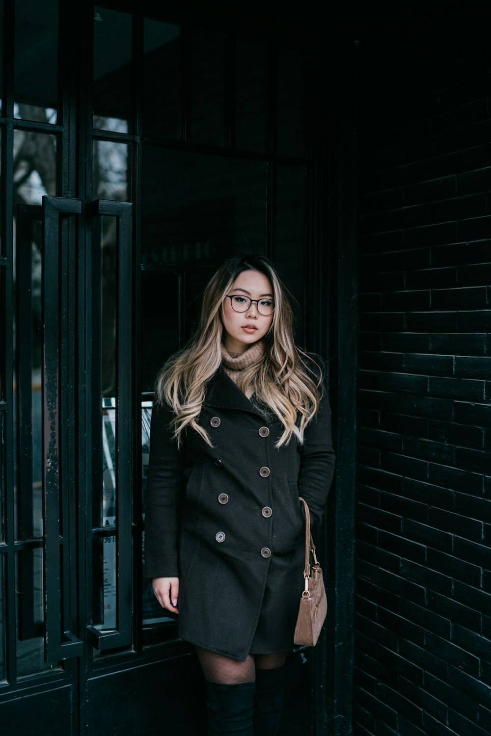 woman in black coat standing beside blue wooden door