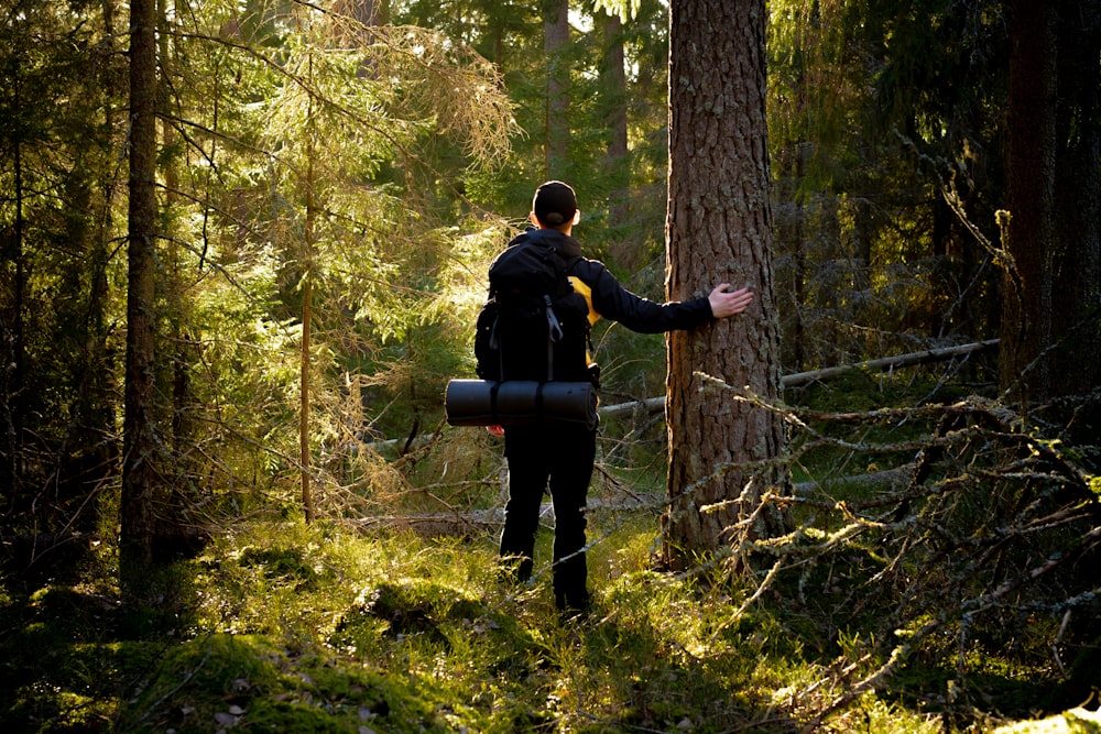 man in black jacket and black pants standing on green grass field surrounded by trees during