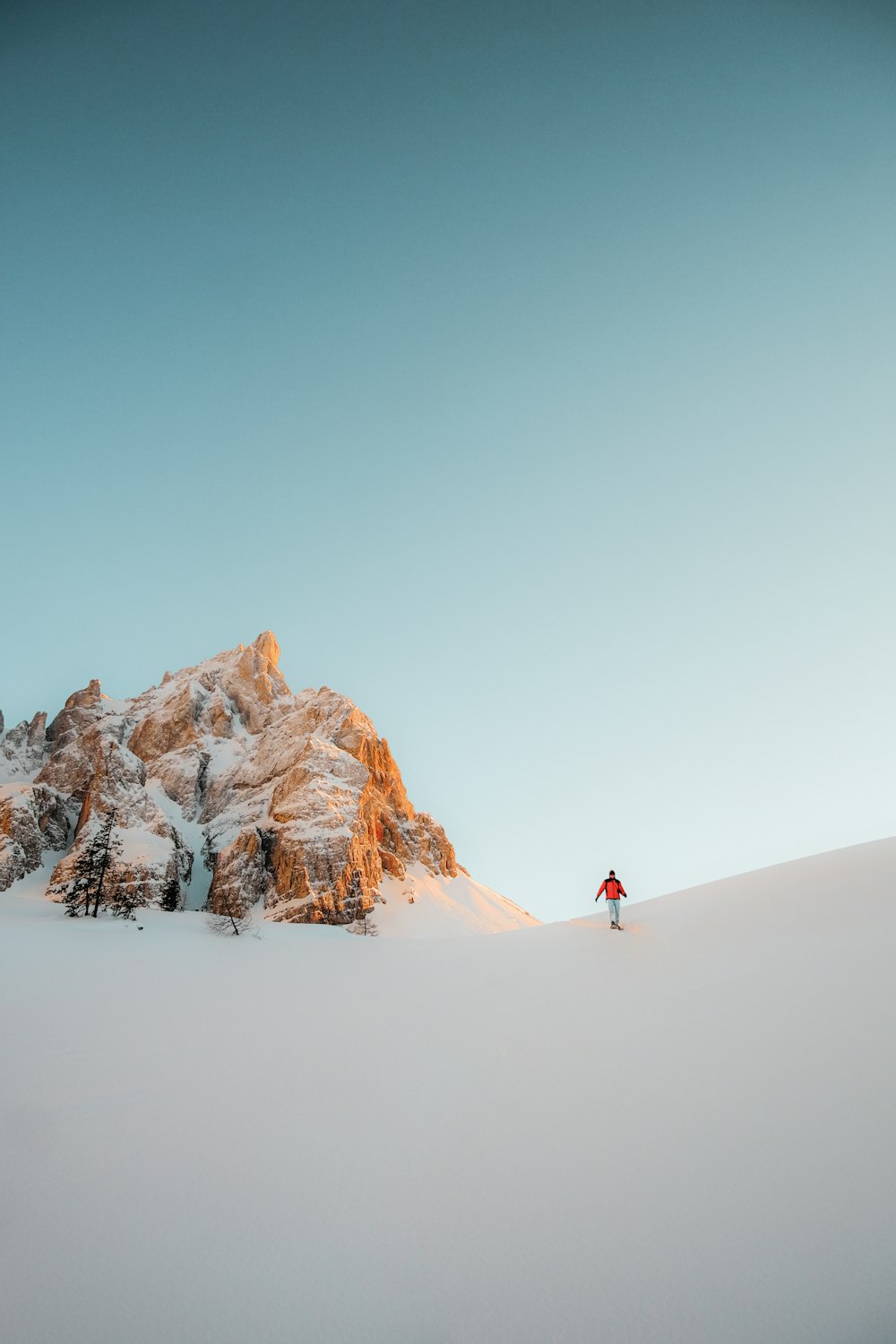 Persona in giacca rossa che cammina su un terreno innevato durante il giorno