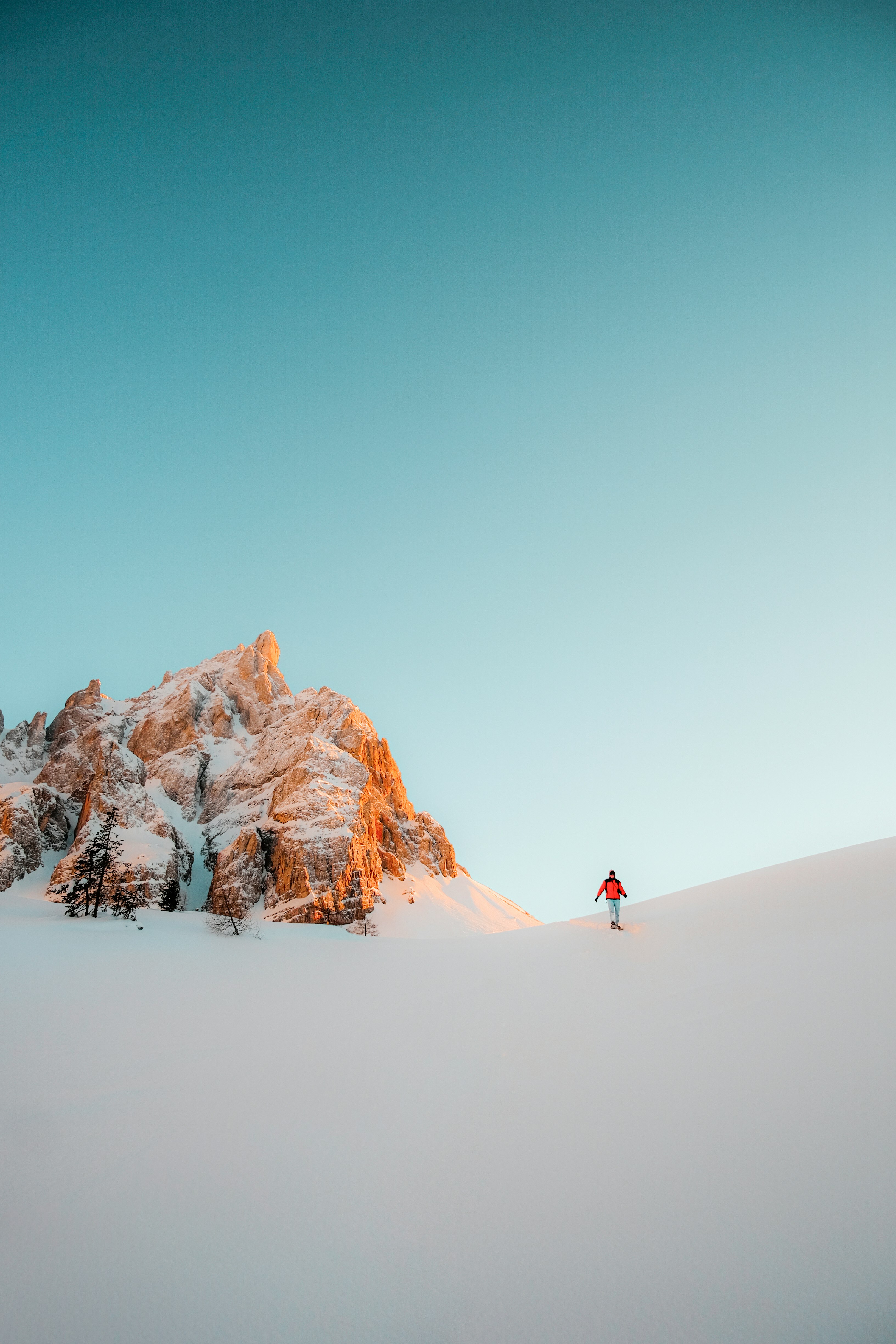 person in red jacket walking on snow covered ground during daytime