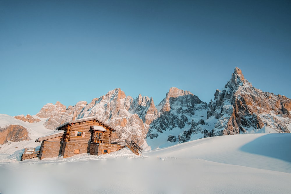 brown house on snow covered ground near snow covered mountain during daytime