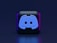 A 3D-style block with a blue logo in the center, set against a dark background. The logo resembles a game controller with two rounded edges and two circles on the front. The block has a subtle gradient, transitioning from dark to purple on its sides.