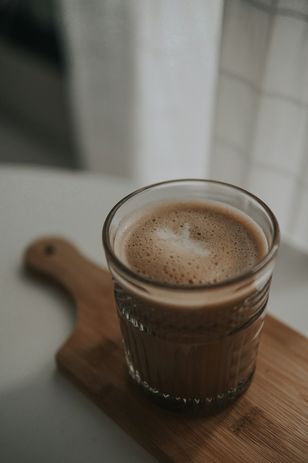 clear drinking glass with brown liquid on brown wooden table