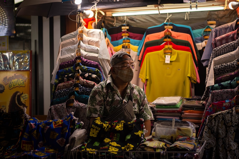 man in green and black floral dress shirt standing near clothes display