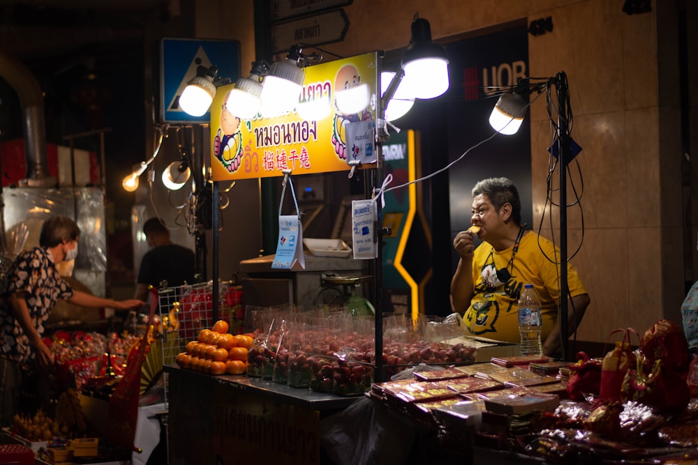 man in yellow polo shirt standing in front of fruit stand