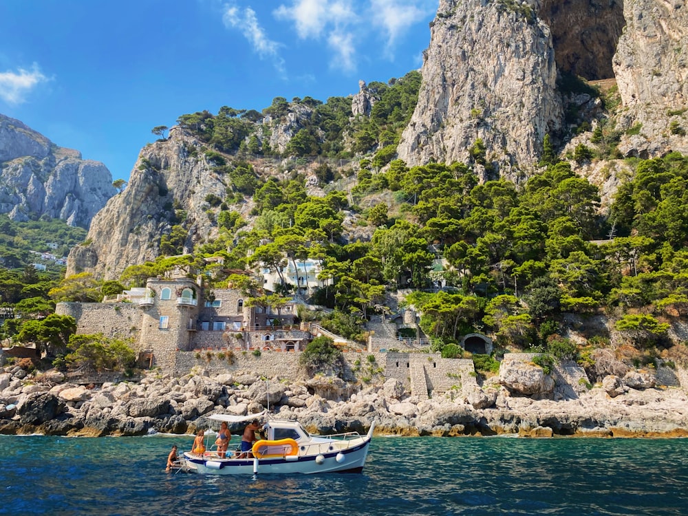 Barca bianca e arancione sul mare vicino alla montagna durante il giorno