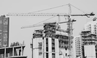 grayscale photo of building with tower crane