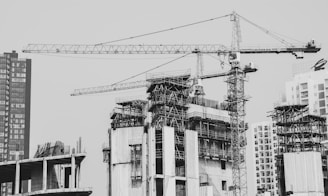 grayscale photo of building with tower crane