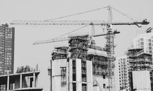grayscale photo of building with tower crane