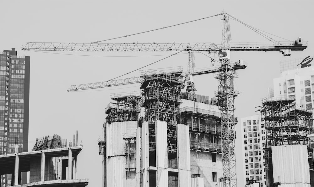 grayscale photo of building with tower crane