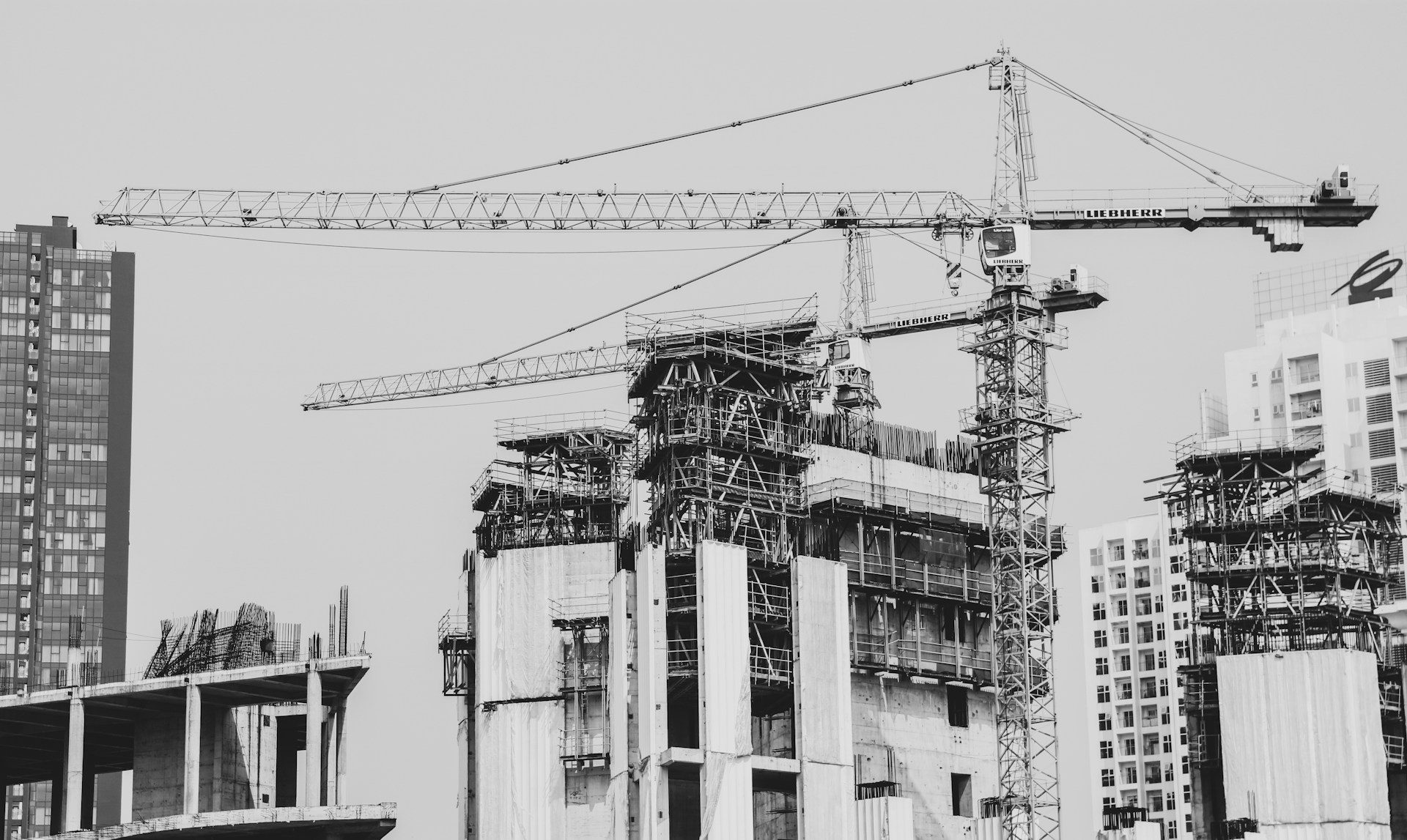 grayscale photo of building with tower crane