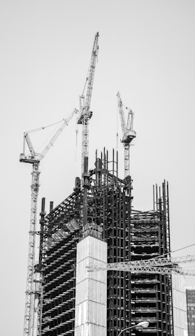 grayscale photo of crane near building
