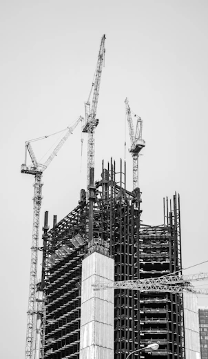 grayscale photo of crane near building
