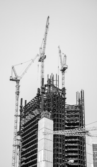 grayscale photo of crane near building