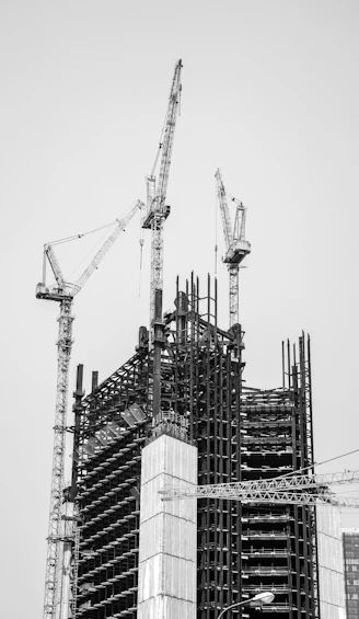 grayscale photo of crane near building