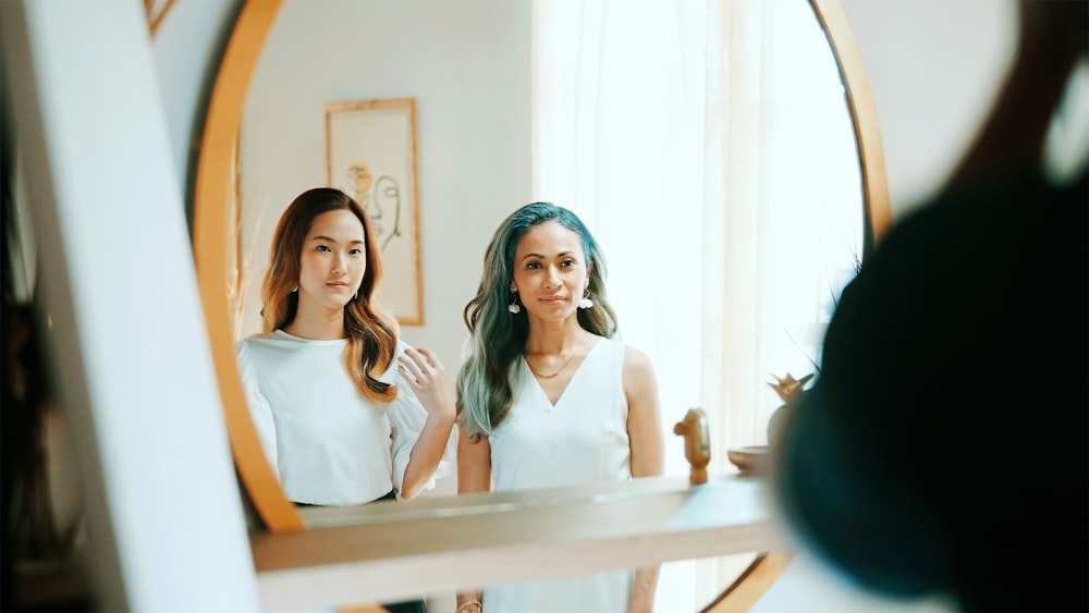 2 women in white sleeveless shirt sitting on chair