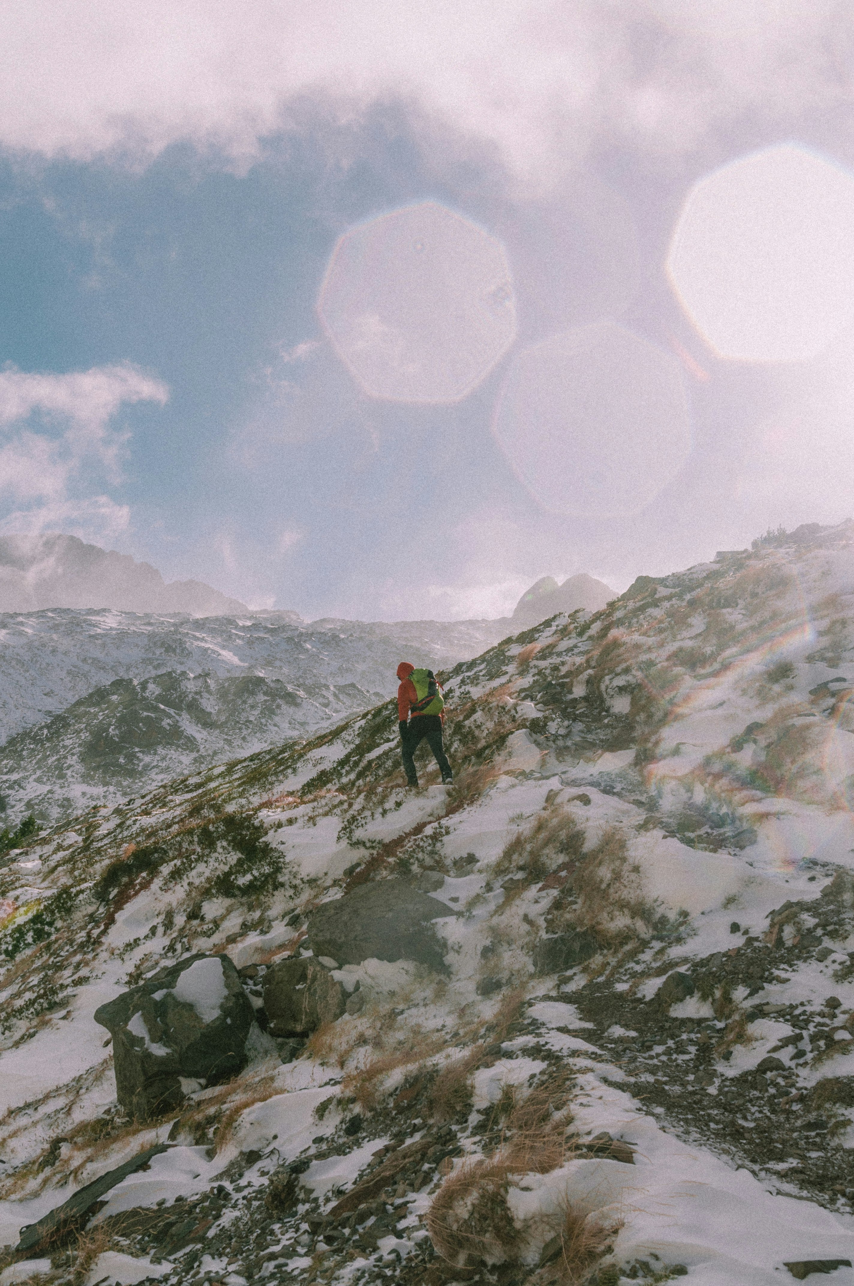 person in red jacket standing on snow covered mountain during daytime