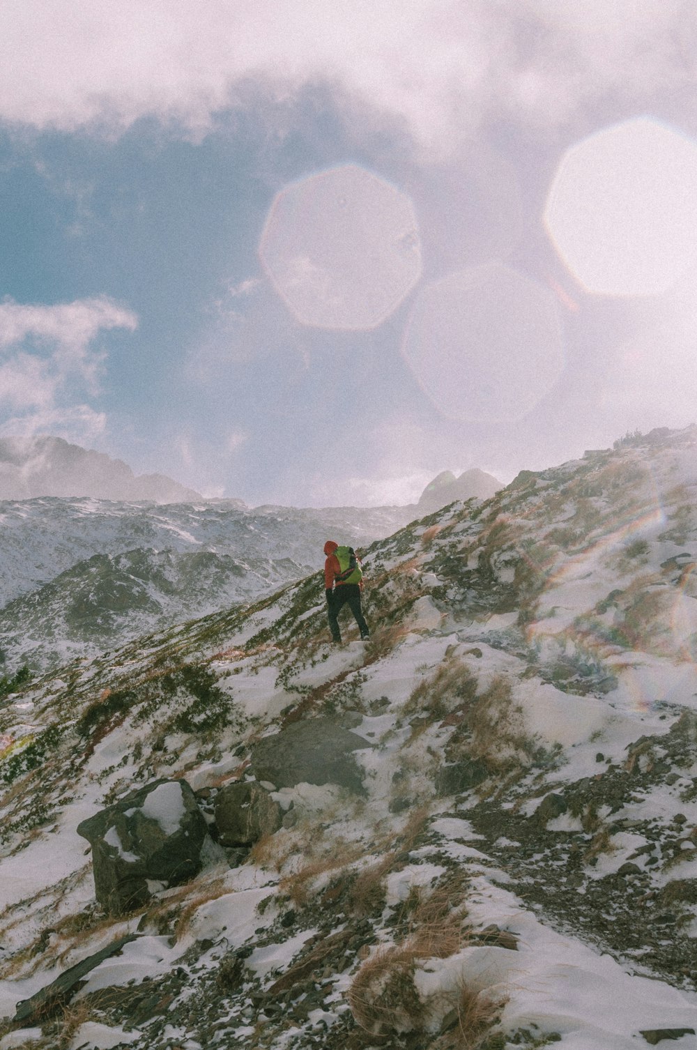 person in red jacket standing on snow covered mountain during daytime