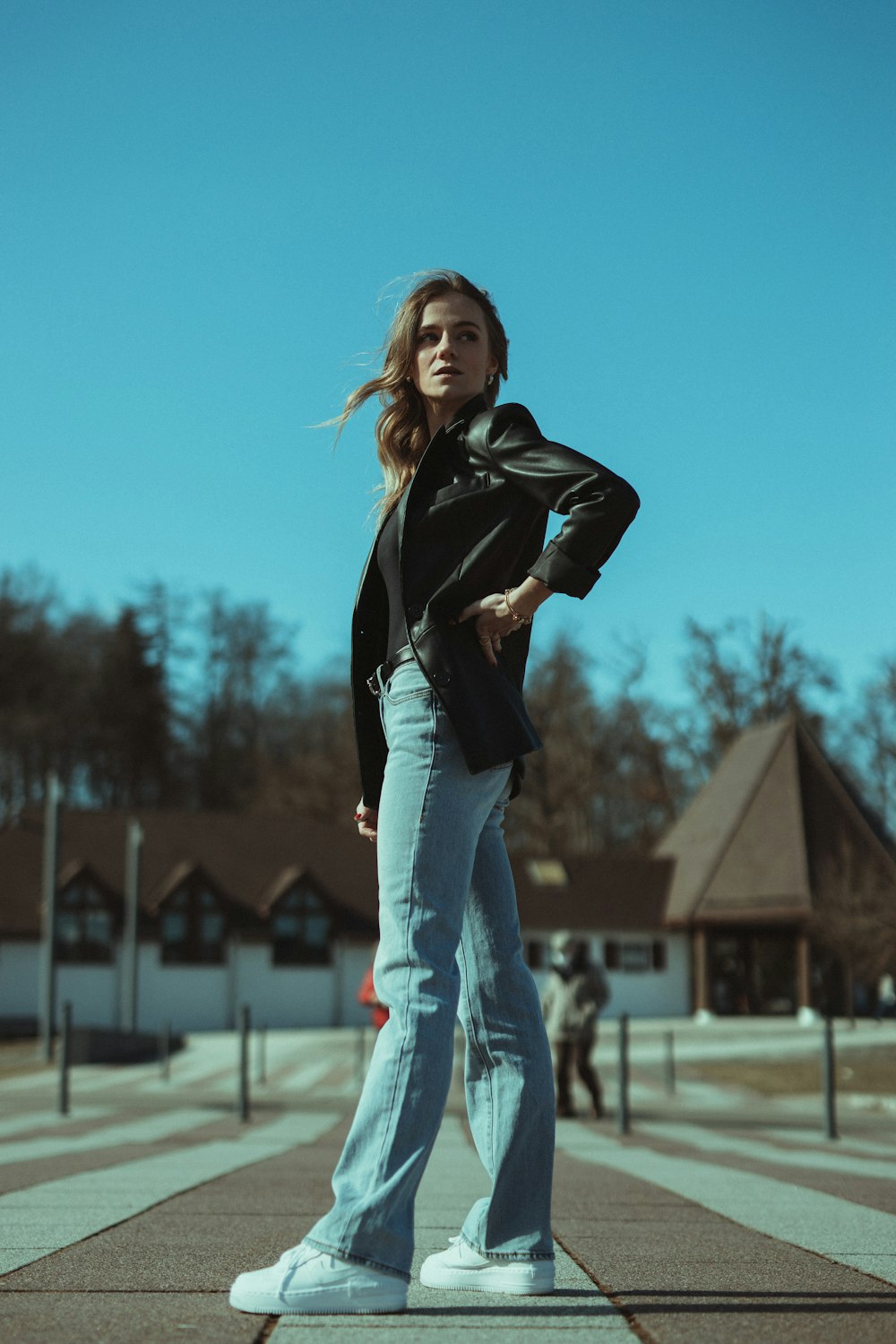 Frau in schwarzer Lederjacke und blauer Jeans tagsüber auf dem Feld