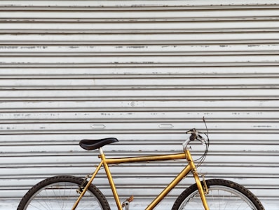 yellow and black bicycle leaning on white wall