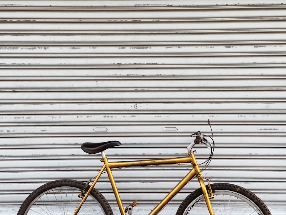 yellow and black bicycle leaning on white wall