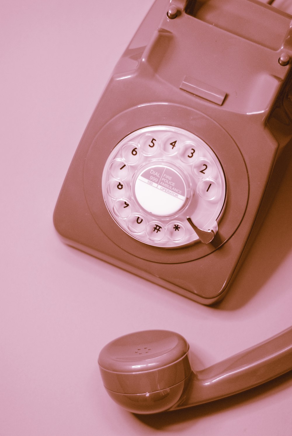 Teléfono de disco blanco sobre mesa rosa