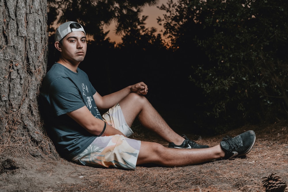 man in black crew neck t-shirt and white shorts sitting on brown soil during daytime