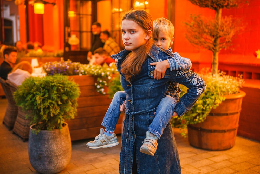 Mädchen in blauer Jeans sitzt auf braunem Holzsitz