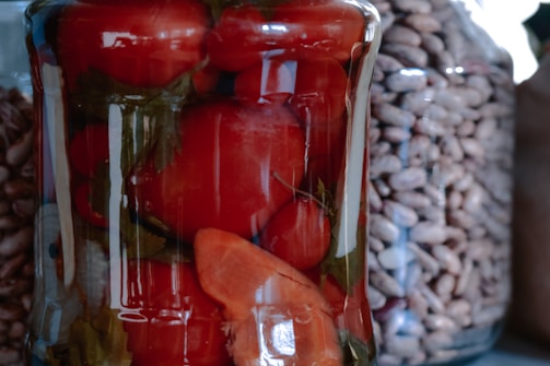 Close-up of a vibrant jar of spicy jam with fresh chili peppers beside it.