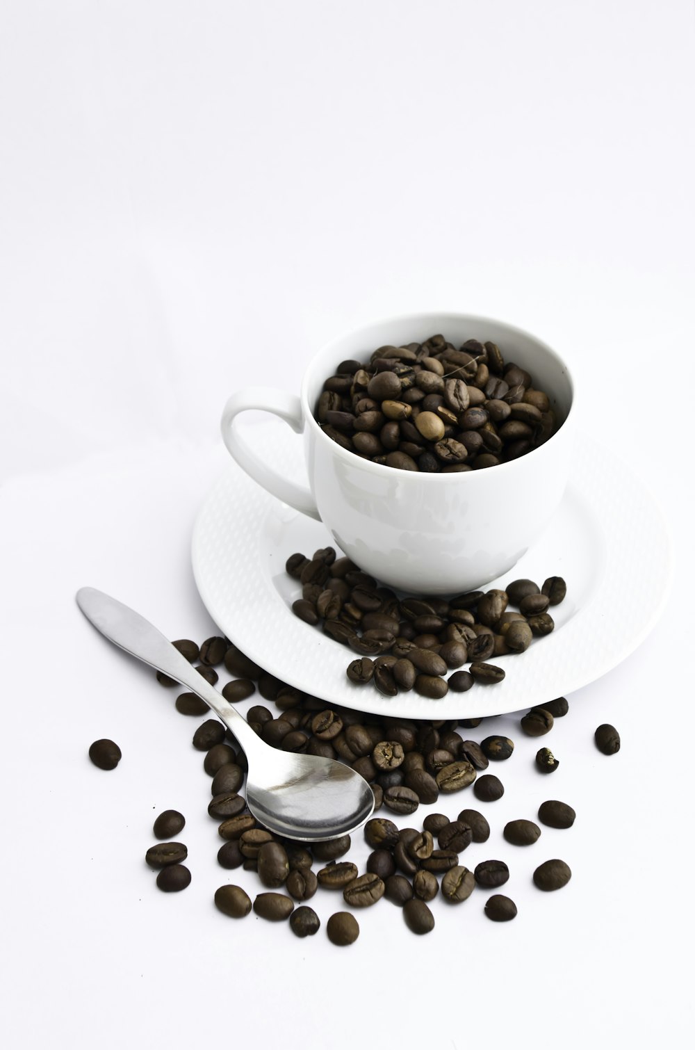 white ceramic teacup with coffee beans