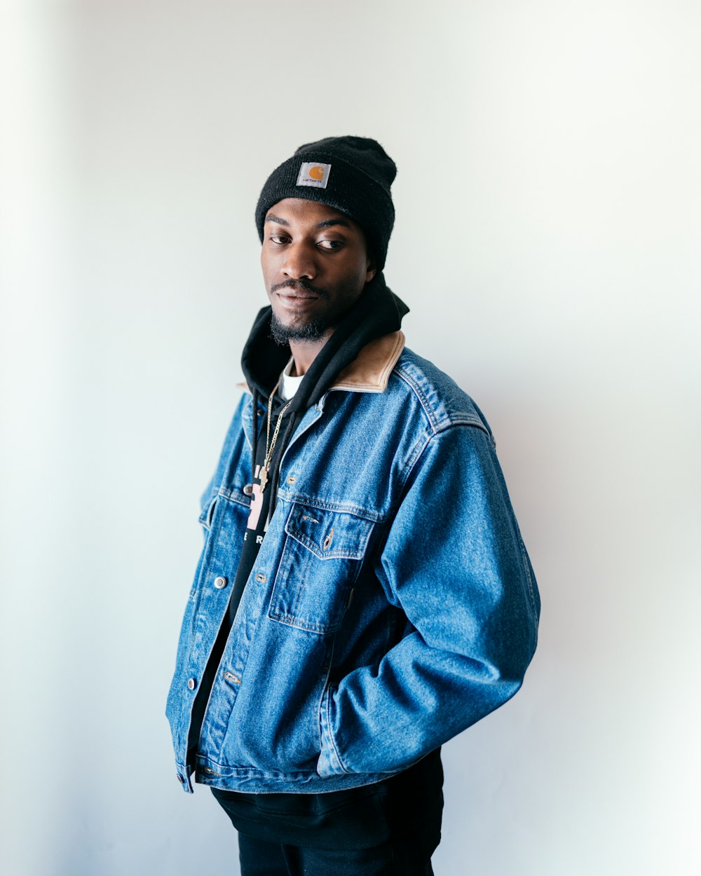 man in blue denim jacket wearing black cap