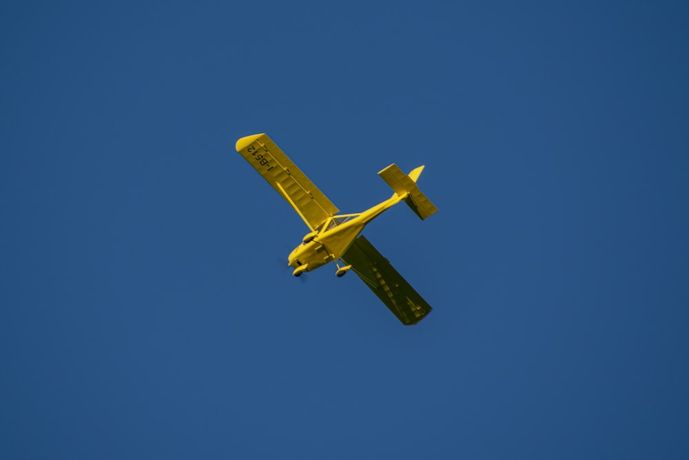 yellow plane in mid air during daytime