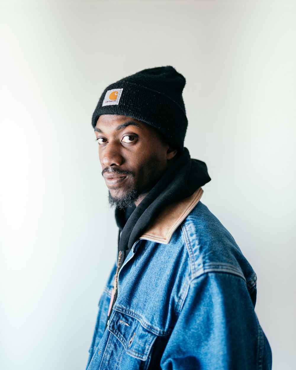 man in blue denim jacket wearing black cap