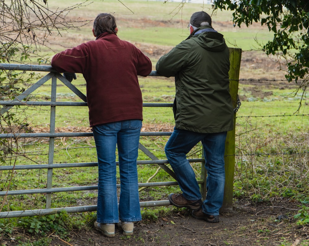 man and woman standing beside fence during daytime